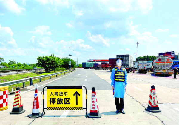     工作人員在廣惠高速服務區入口引導入粵貨車到停放專區停車。