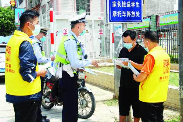     交警和志愿者向市民宣傳文明出行。