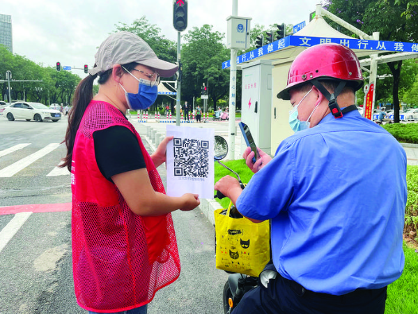 志愿者引導電動車主掃碼“智惠勸導行為”。 惠州日報記者彭紅霞 通訊員藍利芳 攝